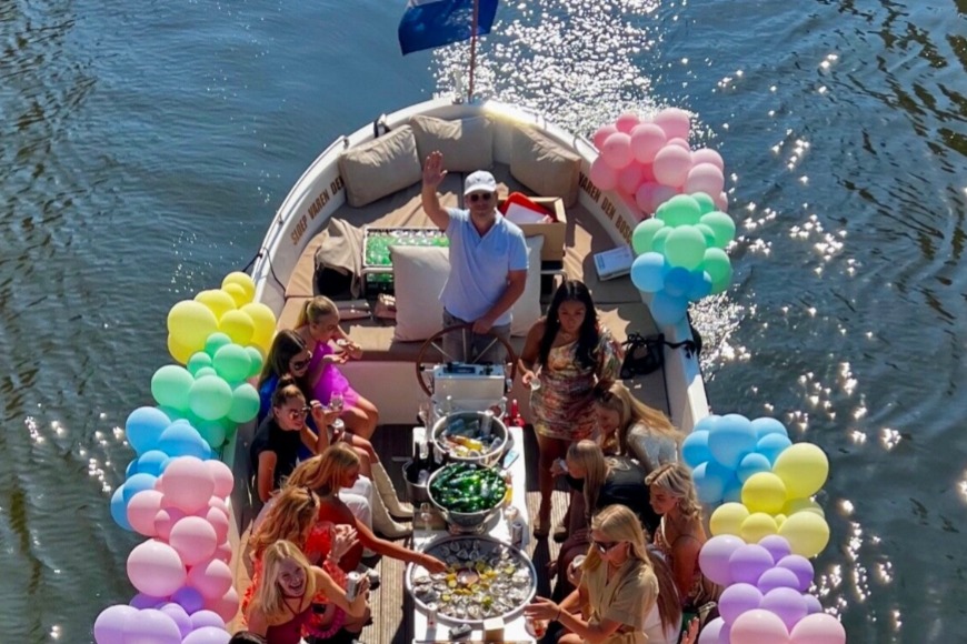 Schipper met een groep dames in een sloep met ballonnen. 
